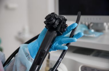An endoscopist in blue gloves holds an endoscope in his hands. In the frame only the hands with the device are close-up An endoscopist in blue gloves holds an endoscope in his hands. In the frame only the hands with the device are close-up. High quality photo
